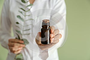 Pharmacologist with bottle of eucalyptus essential oil, closeup