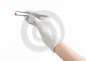 Pharmacology and Medical theme: doctor's hand in a white glove holding tweezers with red pill capsule isolated on white background