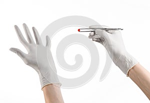 Pharmacology and Medical theme: doctor's hand in a white glove holding tweezers with red pill capsule isolated on white background