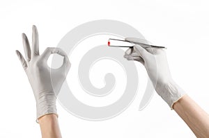 Pharmacology and Medical theme: doctor's hand in a white glove holding tweezers with red pill capsule isolated on white background