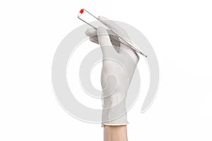 Pharmacology and Medical theme: doctor's hand in a white glove holding tweezers with red pill capsule isolated on white background