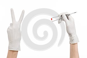 Pharmacology and Medical theme: doctor's hand in a white glove holding tweezers with red pill capsule isolated on white background