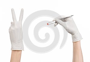 Pharmacology and Medical theme: doctor's hand in a white glove holding tweezers with red pill capsule isolated on white background