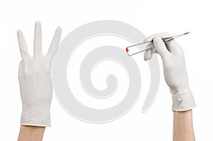 Pharmacology and Medical theme: doctor's hand in a white glove holding tweezers with red pill capsule isolated on white background