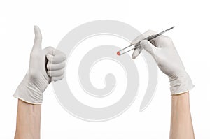 Pharmacology and Medical theme: doctor's hand in a white glove holding tweezers with red pill capsule isolated on white background