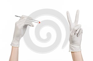 Pharmacology and Medical theme: doctor's hand in a white glove holding tweezers with red pill capsule isolated on white background