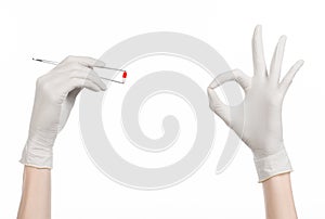 Pharmacology and Medical theme: doctor's hand in a white glove holding tweezers with red pill capsule isolated on white background