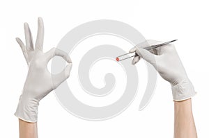 Pharmacology and Medical theme: doctor's hand in a white glove holding tweezers with red pill capsule isolated on white background