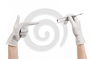 Pharmacology and Medical theme: doctor's hand in a white glove holding tweezers with red pill capsule isolated on white background