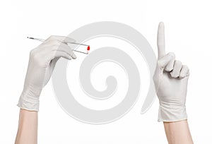 Pharmacology and Medical theme: doctor's hand in a white glove holding tweezers with red pill capsule isolated on white background