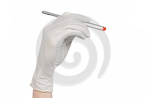 Pharmacology and Medical theme: doctor's hand in a white glove holding tweezers with red pill capsule isolated on white background photo