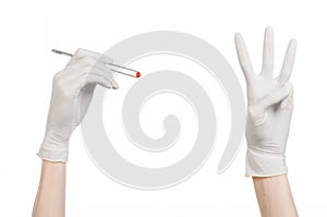 Pharmacology and Medical theme: doctor's hand in a white glove holding tweezers with red pill capsule isolated on white background