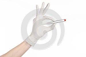 Pharmacology and Medical theme: doctor's hand in a white glove holding tweezers with red pill capsule isolated on white background