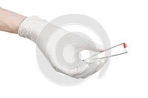 Pharmacology and Medical theme: doctor's hand in a white glove holding tweezers with red pill capsule isolated on white background