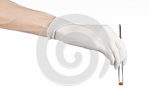 Pharmacology and Medical theme: doctor's hand in a white glove holding tweezers with red pill capsule isolated on white background