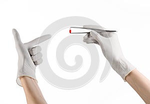 Pharmacology and Medical theme: doctor's hand in a white glove holding tweezers with red pill capsule isolated on white background