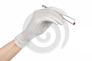 Pharmacology and Medical theme: doctor's hand in a white glove holding tweezers with red pill capsule isolated on white background