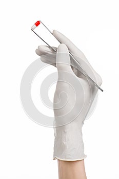 Pharmacology and Medical theme: doctor's hand in a white glove holding tweezers with red pill capsule isolated on white background