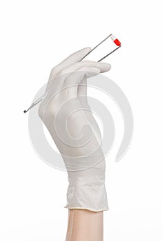 Pharmacology and Medical theme: doctor's hand in a white glove holding tweezers with red pill capsule isolated on white background