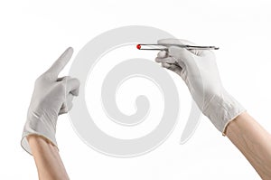 Pharmacology and Medical theme: doctor's hand in a white glove holding tweezers with red pill capsule isolated on white background