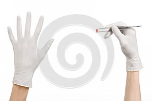 Pharmacology and Medical theme: doctor's hand in a white glove holding tweezers with red pill capsule isolated on white background