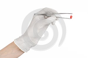 Pharmacology and Medical theme: doctor's hand in a white glove holding tweezers with red pill capsule isolated on white background