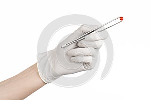 Pharmacology and Medical theme: doctor's hand in a white glove holding tweezers with red pill capsule isolated on white background