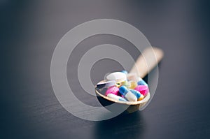 Pharmacy background on a black table with measuring tape. Tablets on a wooden spoon. Pills. Medicine and healthy. Close up of caps