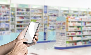 Pharmacy background. Blur counters of pharmacy with medicines, tablets, pills and hand with smartphone