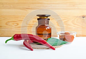 Pharmacy bottle with red chili pepper extract tincture, infusion, oil and fresh chili pepper pods.