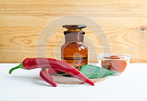 Pharmacy bottle with red chili pepper extract tincture, infusion, oil and fresh chili pepper pods. photo