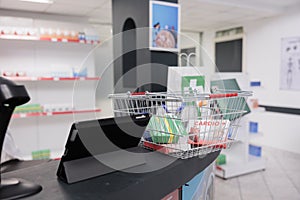 Pharmacy counter was cluttered with shopping basket filled with boxes and packages of various medical supplies