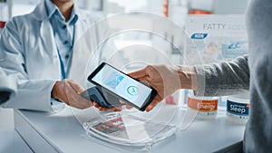 Pharmacy Drugstore Checkout Cashier Counter: Pharmacist and a Customer Using NFC Smartphone with