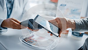 Pharmacy Drugstore Checkout Cashier Counter: Pharmacist and a Customer Using NFC Smartphone with