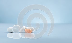 Pharmacy drugstore product. Pile of orange and white tablets pill on gradient background. Different size and shape tablets pills.