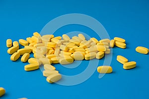 Pharmacy industry concept many yellow pills tablets on blue background