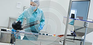 Pharmacy industry woman worker in protective clothing operating production of tablets in sterile working conditions