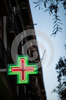 Pharmacy sign illuminated at night on spanish architecture facade photo