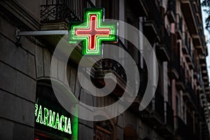 Pharmacy signs illuminated at night on spanish architecture facade photo