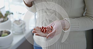 pharmacy and treatment concept - close up view of Caucasian woman pours capsules from a jar into her palm