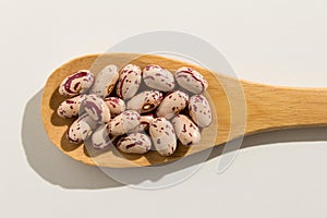 Sugar Bean legume. Nutritious grains on a wooden spoon on white photo