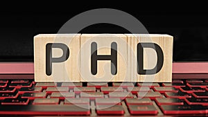 PhD the inscription on wooden cubes on the illuminated laptop keyboard