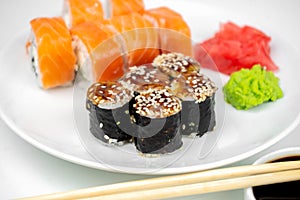 Philadelphia maki rolls and eel unagi maki with soy sauce, pink ginger, wasabi on white background, asian food, japanese sushi set