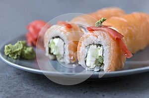 Philadelphia rolls with salmon, ginger and wasabi on a grey plate on a dark background