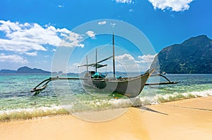 Philippine boat on wave against the blue warm sea and mountains