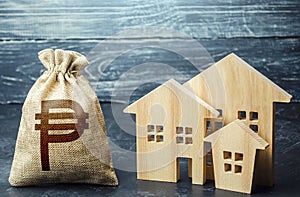Philippine peso money bag and figurines of residential buildings. Property tax. Municipal budgeting. Increase investment
