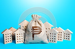 Philippine peso money bag among town houses figurines. Rental business. Municipal budgeting. Rich city. Realtor services. Sale of
