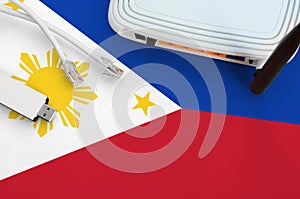 Philippines flag depicted on table with internet rj45 cable, wireless usb wifi adapter and router. Internet connection concept