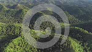 Philippines green jungle mountains aerial view. Small farm building at hillside grassy valley
