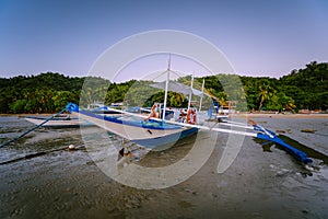 The Philippines`s Banca boat. Traditional fishing boat on beach during low tide in evening light. El Nido,Palawan